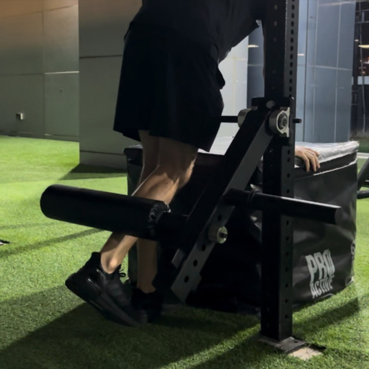 Gymless leg curl and extension attachment mounted on a rack, used for single leg hamstring curls in a home gym.