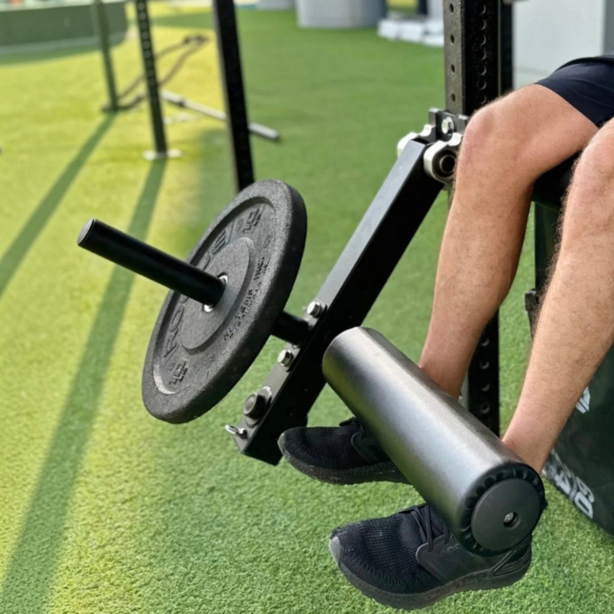 Gymless leg curl and extension attachment mounted on a rack with a weight plate for home gym leg training