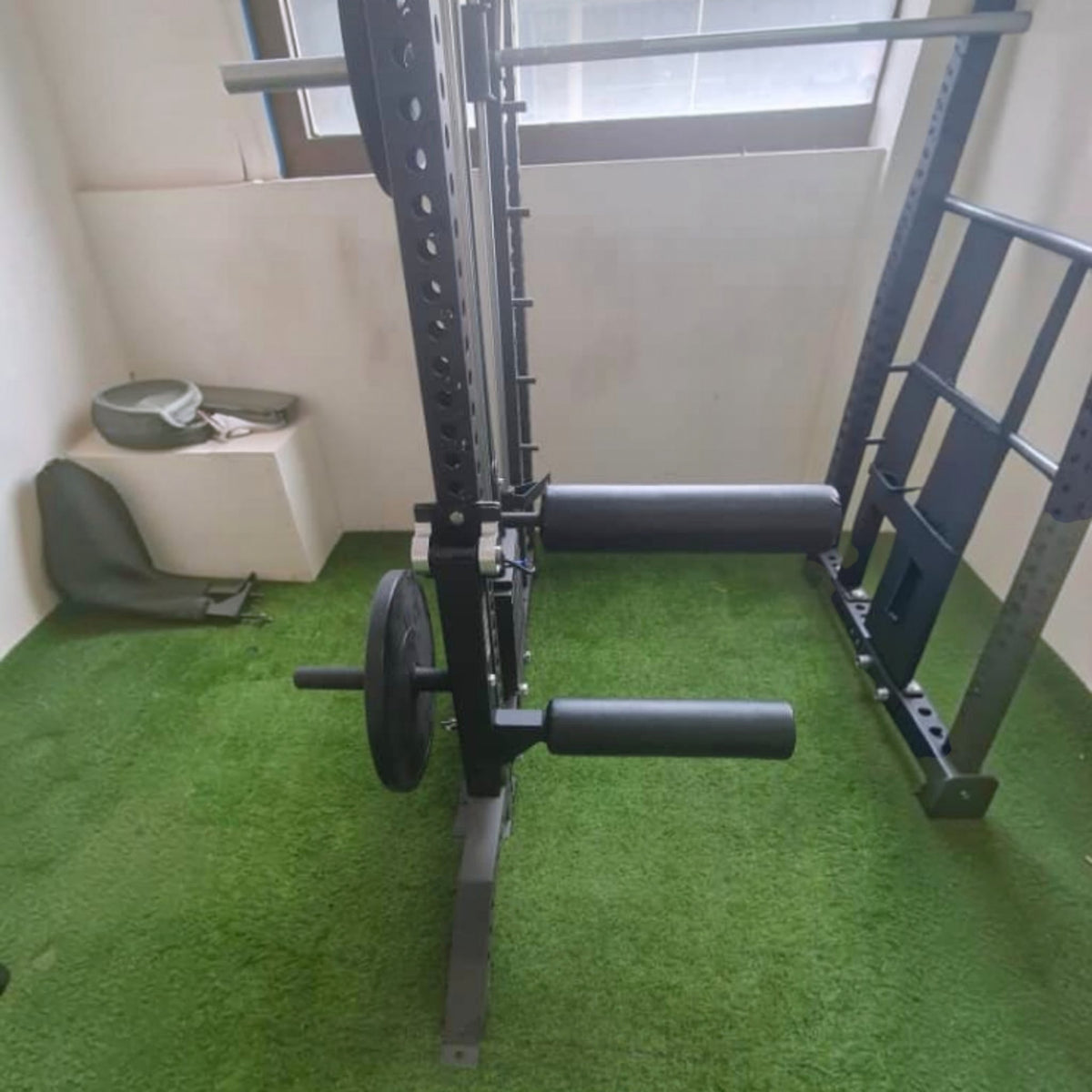 Gymless black steel leg curl and extension attachment mounted on a power rack for home gym strength training