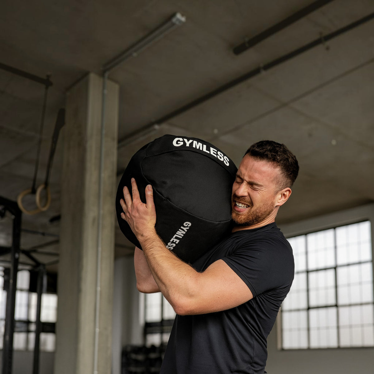 Strongman sandbags being lifted by a man in a gym setting, showcasing strength training.